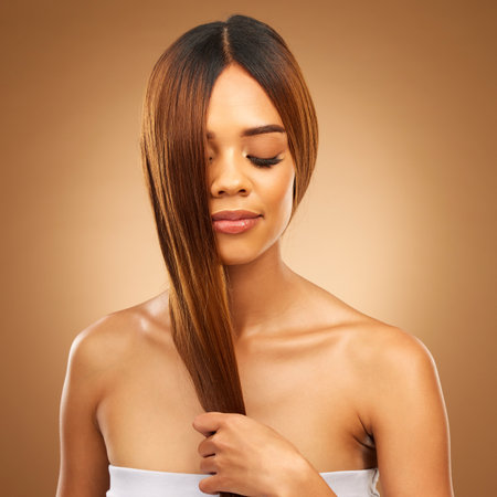 Haircare, studio and woman with hair in hand, strong with bronze texture and salon shine. Wellness model, mockup and spa beauty, healthy straight hairstyle with keratin product on brown background.の写真素材