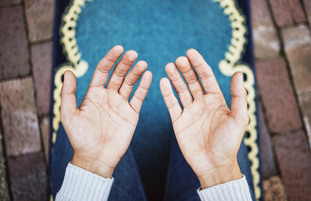 Hands, muslim and praying in worship to Allah, god or creator on salah mat making dua on the floor. Hand of islamic man in pray for islam religion, spiritual or respect for belief or culture outsideの写真素材