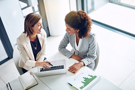 Working together on some grand plans for success. two corporate businesswomen working together on a laptop in an office.の写真素材