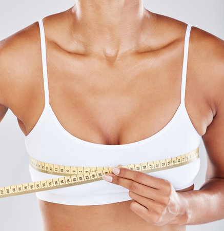 Chest, measure tape and woman isolated on white background for breast cosmetics, plastic surgery and lose weight. Liposuction, health or wellness person or model with boobs for beauty results in zoomの写真素材