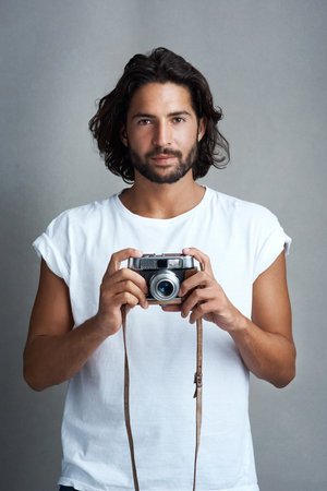 Are your ready for me. Studio portrait of a young man posing with a vintage camera against a grey background.の写真素材