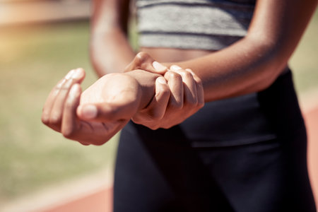 Hands, runner and arm injury from sports exercise, workout or training at the stadium track. Active female suffering in joint inflammation holding painful wrist in discomfort, strain or sore bruiseの写真素材