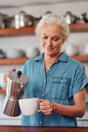 The kickstarter of mornings everywhere. a mature woman making coffee in the kitchen at home.の写真素材