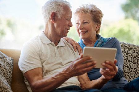Its hard to imagine how we ever lived without it. a happy senior couple using a digital tablet together on the sofa at home.の写真素材