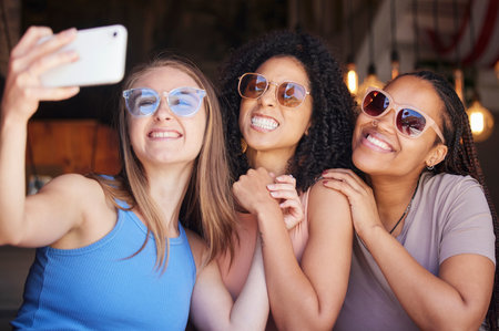 Sunglasses, friends and selfie with women in restaurant for social media, freedom and support. Happy, diversity and photo with group of girls in cafe for picture, networking and relax on weekendの写真素材