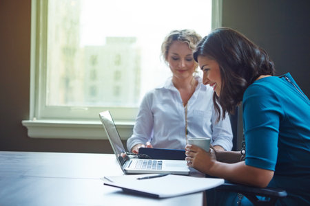 Driven to make their corporate dreams come true. two businesswomen having a meeting together in an office.の写真素材