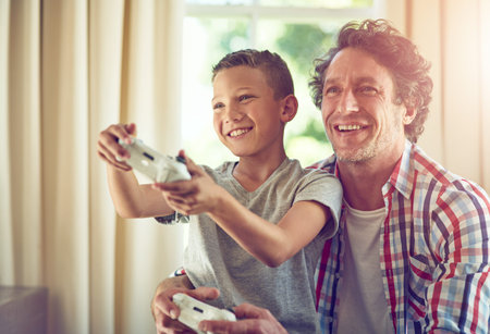 Let your father show you how its done. a father and his son playing video games at home.