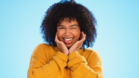 Face, celebration and black woman excited, smile and success with girl on a blue studio background. Portrait, African American female and lady with happiness, winning and victory with joy or cheerfulの写真素材