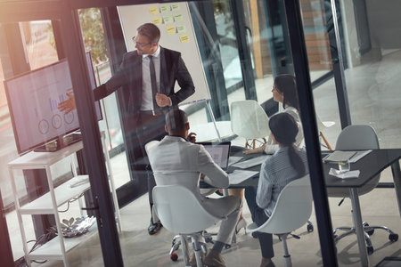 Getting everyone on the same page. a businessman giving a presentation in the boardroom.の写真素材