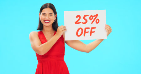 Woman, portrait and sale sign for studio advertising percentage or discount rate on paper or banner. Smile of a happy female on a blue background for fashion promotion deal, savings or deal and offerの写真素材