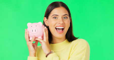 Happy woman, face and money savings on green screen for investment, budget or finance against studio background. Portrait of excited female holding piggybank for coin, profit or investing on mockupの写真素材