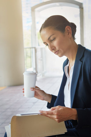 Catching up with work on her commute. a businesswoman reading paperwork while taking a break from...