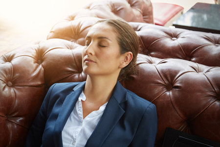 Sweetdreams of success. a young businesswoman sleeping on a sofa.の写真素材