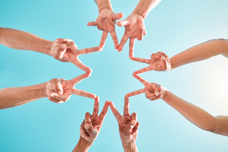 Hands, star and group of people in teamwork, collaboration and support outdoors in a circle for solidarity together. Fingers, community and team making hand sign or shape in the sunshineの写真素材