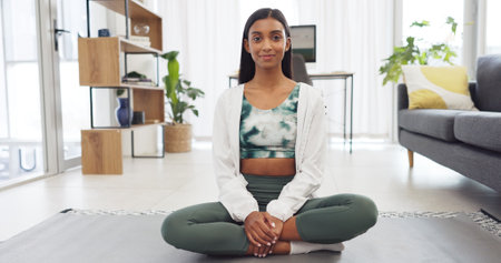 Yoga, fitness and exercise with a woman training with a workout in her home for health and wellness. Healthy, zen and meditation with a young female athlete sitting on a mat in the living roomの写真素材