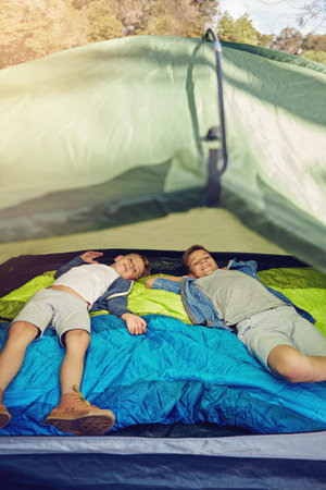 Boys will be boys. two young brothers lying in their tent.の写真素材