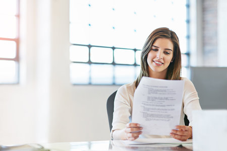 Finalizing the agenda before her management meeting. a young businesswoman reading a document in an office.の写真素材