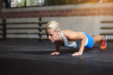 Every workout counts. a young woman doing pushups in a gym.