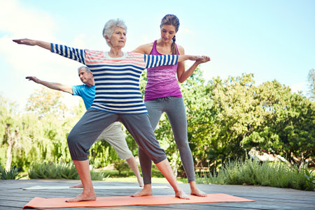 Keep in shape no matter your age. a yoga instructor guiding a senior couple in a yoga class.の写真素材