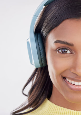 Portrait, headphones and half with a woman in studio on a gray background listening to music. Face, happy and smile with an attractive young female streaming audio using a subscription serviceの写真素材