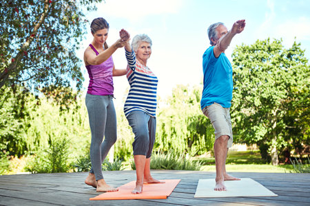 Stay fit in your senior years. a yoga instructor guiding a senior couple in a yoga class.の写真素材