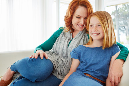 So much love. a mother and young daughter sitting on the sofa at home.