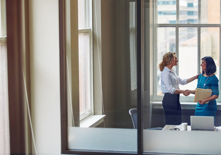 Theres lots of room to grow in this company. two businesswomen shaking hands in an office.の写真素材