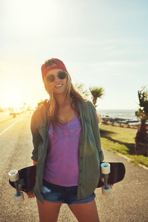 She lives to skate. a young woman hanging out on the boardwalk with her skateboard.