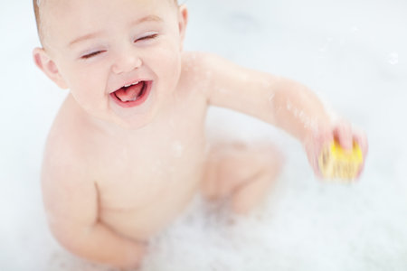 Are you sure Im not suppose to drink the water. an adorable baby boy playing with a toy while bathing.の写真素材