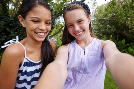 Best friends forever. two young girl friends taking a selfie together outside.の写真素材