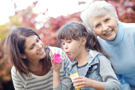 Happiness is blowing bubbles. a three generational family spending time outdoors blowing bubbles.