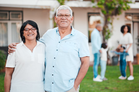 Outdoor, portrait and senior couple by their house embracing while bonding with their family. Love, smile and happy elderly man and woman in retirement standing in the backyard of their modern home.の写真素材