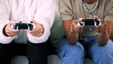 Woman, hands and friends gaming with controller on living room sofa in competitive match or game at home. Women playing video games in competition or esports sitting on lounge couch for entertainmentの写真素材