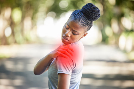 Sports, health and woman with shoulder injury, pain or accident while running in a park. Fitness, workout and African female athlete with a medical emergency or sprain muscle after a cardio exercise.の写真素材