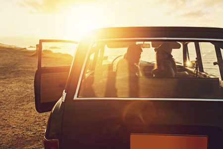 Hop in, were moving on. two friends on a road trip to the beach at sunset.の写真素材