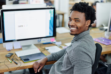 If you can dream it, I can design it. Portrait of an smiling young designer sitting at a computer in...