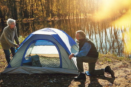 Overnight in nature. a senior couple setting up a tent while camping in the wilderness.