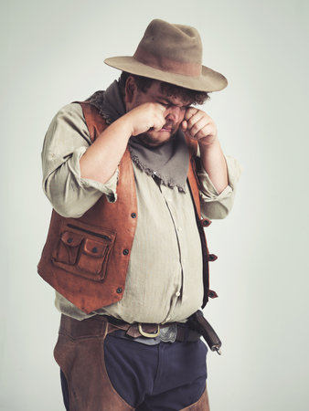 Why wont anyone take me serious. An overweight cowboy crying while isolated on gray.の写真素材
