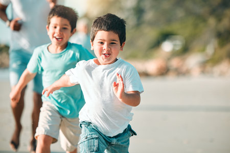 Running, playful and portrait of children at the beach for a holiday, weekend fun and bonding. Happy, freedom and boy kids at the sea in nature to run, play and be free with family on vacationの写真素材
