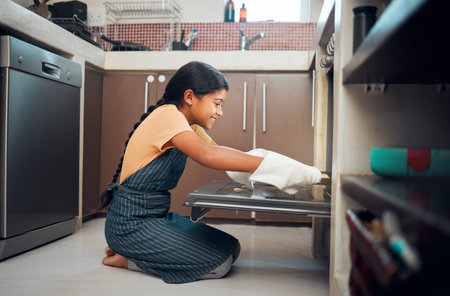 Cooking, oven and girl child in kitchen holding tray after baking in home. Learning, education and happy kid teaching herself how to bake pastry, having fun and enjoying quality time alone in house.の写真素材