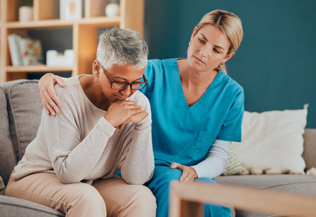 Bad news, support and nurse with a senior patient sitting on a sofa in her office at the hospital. Sad, upset and elderly woman with comfort from healthcare employee after medical diagnosis at clinicの写真素材
