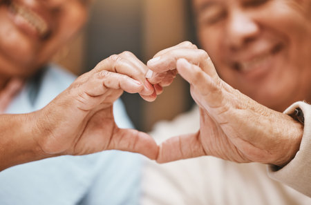 Love, heart hands or happy old couple with support, trust or hope in a marriage commitment at home. Romance, valentines day or senior man smiles with an elderly woman relaxing on anniversaryの写真素材