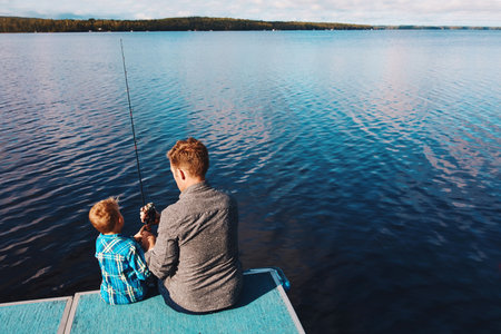 Showing him how to fish. a father and his young son out fishing by the lake.の写真素材