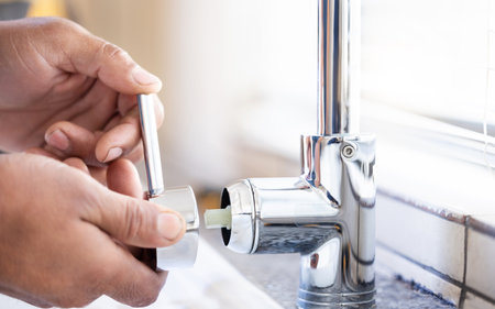 Plumber man, tap and hands of maintenance for installation, home renovation and builder service. Closeup handyman, sink and plumbing handle in house, engineering contractor or upgrade pipeline systemの写真素材