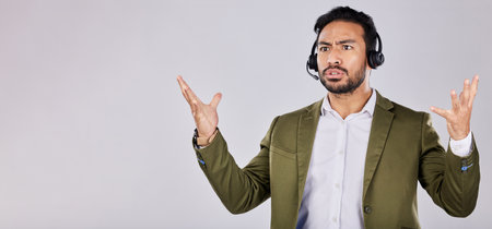 Confused, question and frustrated man call center agent angry isolated against a studio grey background and stress. Employee, ask and rude customer service worker or consultant annoyed at workの写真素材