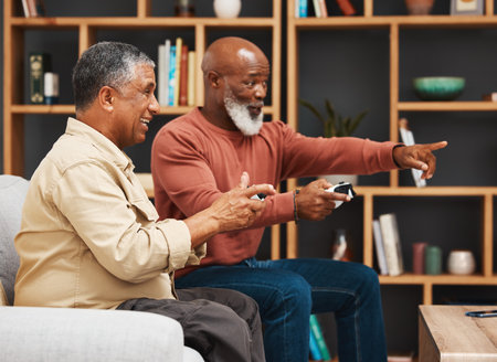 Gaming, pointing and senior black man friends playing a video game together in the living room of a home. Sofa, funny or retirement with a mature male gamer and friend enjoying a house visit to gameの写真素材