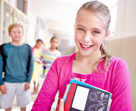 Shes keen on studying. Closeup portrait of a group of young elementary students standing in a school hallway.の写真素材