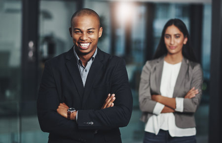 Confidence leaves the most lasting impression. Portrait of a young businessman standing in an office with his colleague in the background.の写真素材