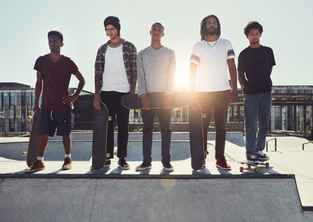 Getting ready to slide through. Full length shot of a group of friends standing together on a ramp at a skatepark.の写真素材