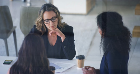 They always find a way to work everything out. High angle shot of three young businesswoman sitting in the boardroom during a management meeting.の写真素材